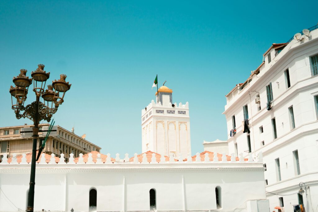 A vibrant scene of Alger Centre featuring historic buildings and the Great Mosque under a clear sky.