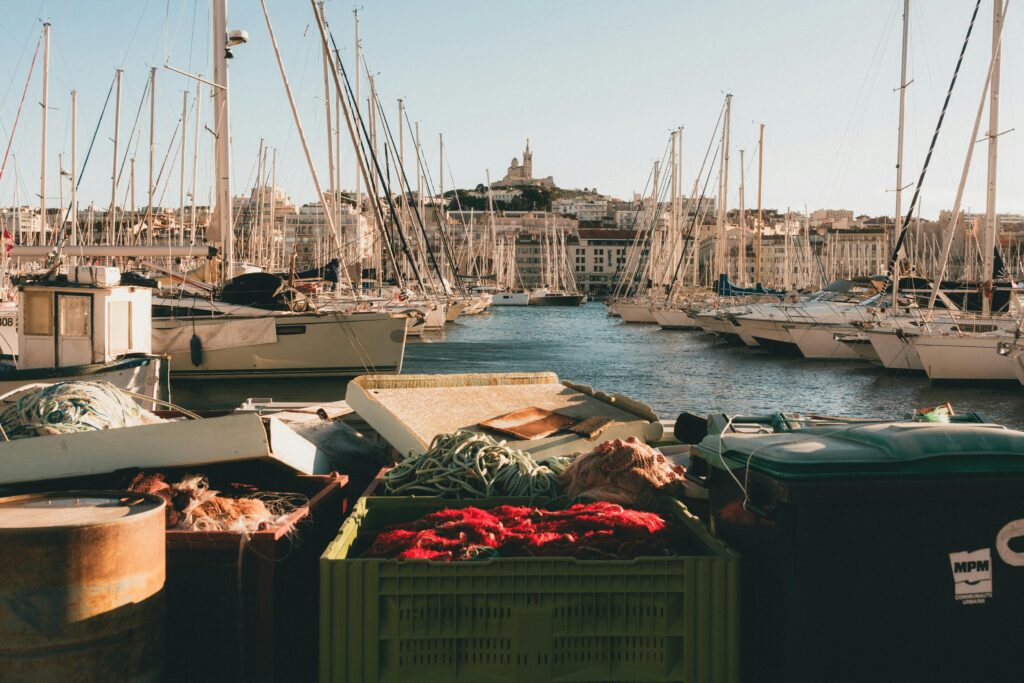 A vibrant scene of Marseille's harbor with yachts and the iconic Notre-Dame de la Garde Basilica.