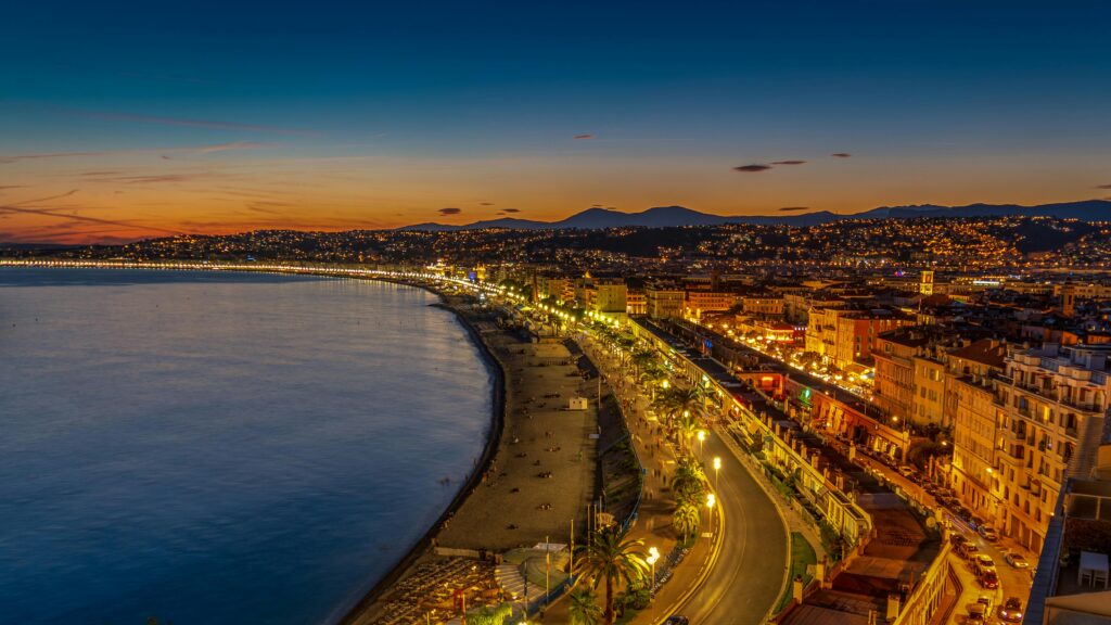 Beautiful twilight view of Nice city and coastline in France, showcasing illuminated streets and scenic bay.